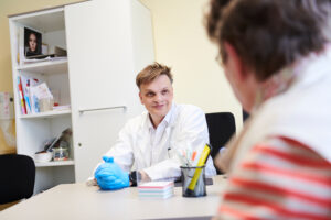 Over shoulder shot from a patient facing the doctor at the desk, smiling back at them.