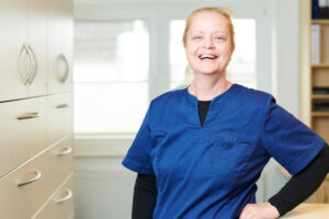 A medical assistant standing in a laboratory and laughing confidently into camera.