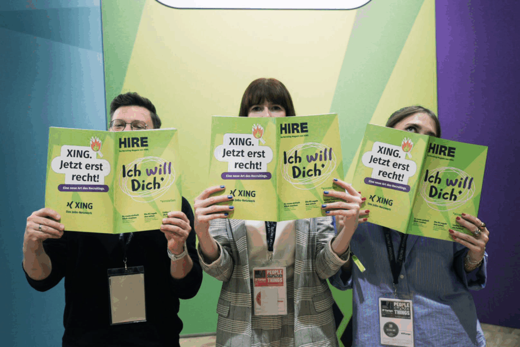 A mood photograph of 3 people cheekily hiding behind an opened copy of the Hire magazine each.